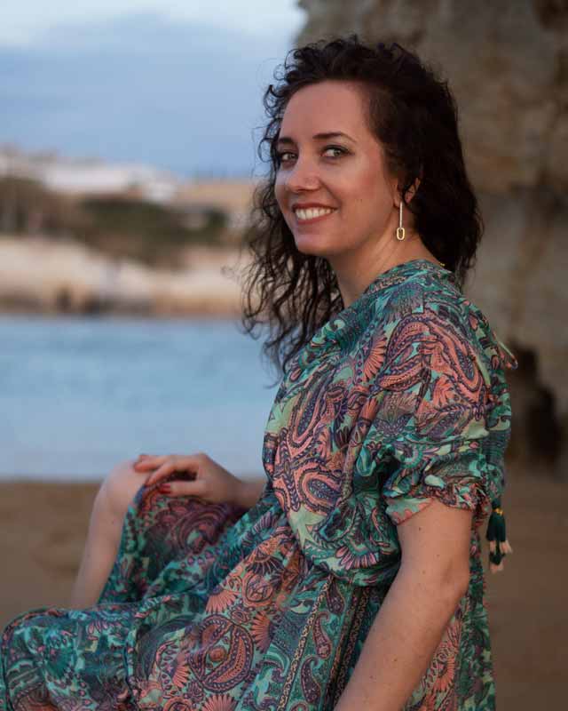 Charlotte Körner am Strand in die Kamera schauend, in einem grünen Kleid.