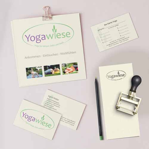 Gedruckte Materialien von oben aufgenommen. Zusehen das Design von Yogawiese. Ein Flyer, eine 8er-Yogakarte. Visitenkarte, Front und Back. Notizzettel, Bleistift und ein Stempel.