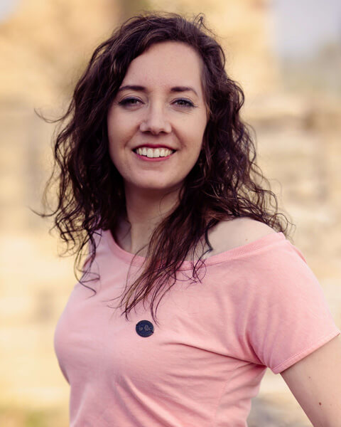 Foto Charlotte Körner Grafikerin mit einem pinkfarbenen T-Shirt in der Natur.
